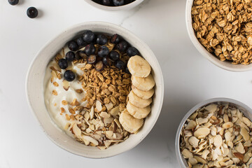 Homemade granola with Greek yogurt, almonds, blueberries and banana in a bowl. 