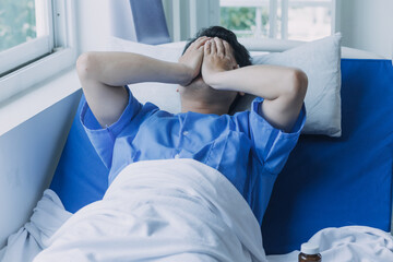 young injured man in hospital room sitting alone in pain looking negative and worried for his bad...