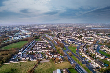 Fototapeta na wymiar High density residential area in Galway city, Ireland. Sunset sky and warm and cold colors. Aerial view. Town houses in close proximity to each other. Private property.