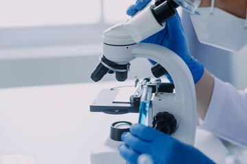 biochemical research scientist team working with microscope for coronavirus vaccine development in pharmaceutical research labolatory, selective focus