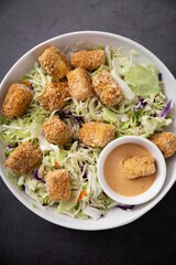 a white plate topped with green salad and tofu bites
