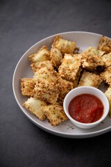 White bowl filled with toasted ravioli and a savory dipping sauce
