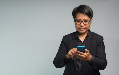 Portrait of a businesswoman with short black hair using a smartphone with a smile while standing on...