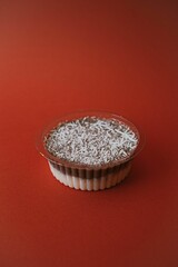 Vertical shot of a plastic bowl of creamy pudding on a red background