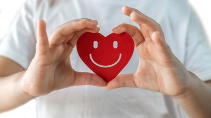 Human hand holding red heart face smile paper cut, health and medical, love, happy, relax,...