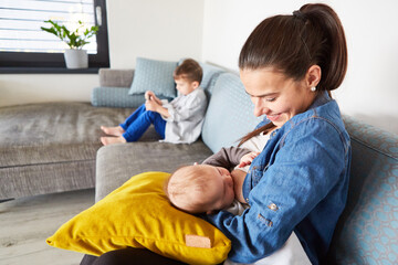 Happy mother breastfeeding baby on sofa