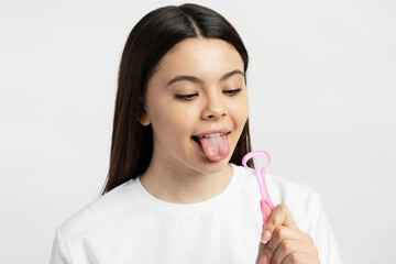 Young caucasian girl cleaning tongue isolated on white background. Health care, mouth hygiene  - obrazy, fototapety, plakaty