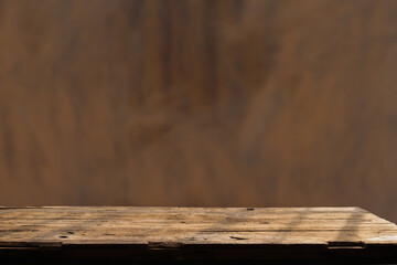 Empty wooden board on table top and blur inside over stucco wall blur background, mock up for display of goods.