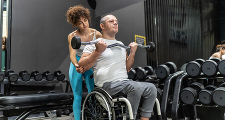 In a display of strength and inclusivity, a person in a wheelchair engages in a workout session with the help of a supportive female fitness instructor.	

