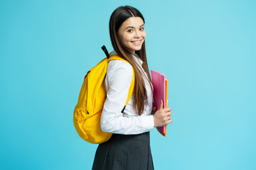 Portrait of smiling pretty girl wearing school uniform, yellow backpack holding notebooks looking...