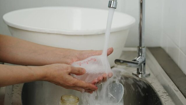 mother hand washing the baby plastic milk bottle