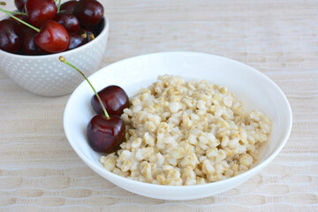 A bowl of oatmeal with two cherries in it isolated, close-up 