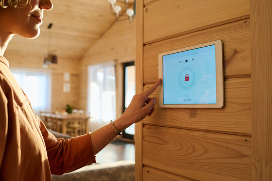 Hand of young woman on panel of alarm system with lock sign on screen during process of uploading, reloading or changing settings