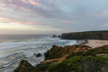 Beautiful shot of sea waves covering a sandy coastline under a cloudy sky