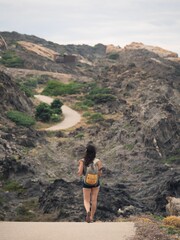 Naklejka premium Aerial view of female walking through road in background of rocky mountains in Cap de Creus