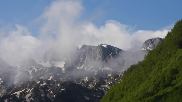 Enchanting Dance of White Clouds: Dynamic Movement Across Snow-Covered Slopes in the Majestic Alpine Mountains in Albania