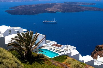 High-angle of the white house with a pool on top of the blue sea on Santorini island, Greece