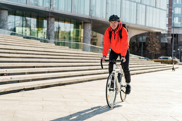 Courier delivery of documents and materials for the office. A male cyclist in a helmet riding a bicycle ecotransport to work with a bag.