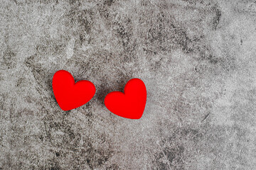 Two red hearts on a gray concrete background.