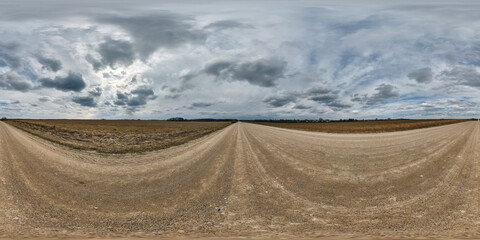 gravel road with clouds on overcast sky as spherical 360 hdri panorama in equirectangular seamless...
