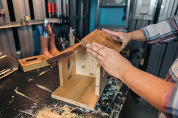 Carpenter's hands assembling a wooden bird house