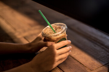 Fototapeta na wymiar Warm Morning Brew: Coffee Hands Holding a Cup on Sunlit Wooden Table