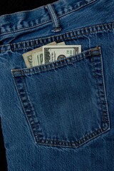 A vertical shot of dollar bills in a back pocket of jeans
