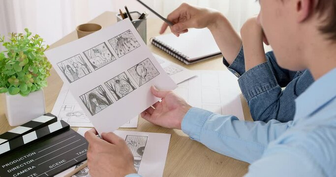 The storyboard for the film is in the hands of the director. Drawn characters on paper.	