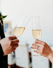 Vertical shot of the bride and the bridegroom holding glasses of champagne on the wedding day