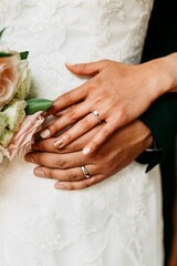 Vertical shot of the bride and the bridegroom holding hands with rings during the wedding ceremony