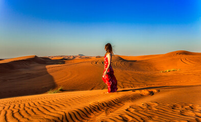 Woman in red walking on a dunes