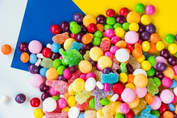 Top view of different candies on a blue and yellow background
