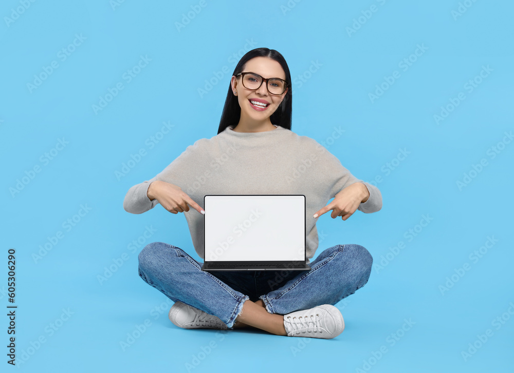 Canvas Prints Happy woman pointing at laptop on light blue background