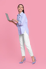 Happy woman with laptop on pink background