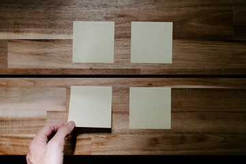 Top view closeup of a person attacking sticky note papers on a wooden table