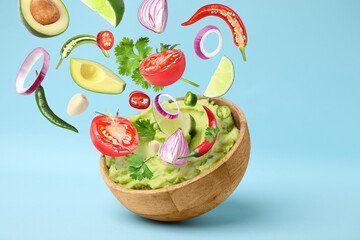 Delicious guacamole with flying ingredients on light blue background