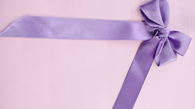 Closeup of a person putting a purple bow on the pink empty surface