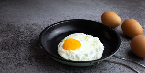 Top view of Breakfast menu fried eggs in an iron pan and raw chicken eggs.