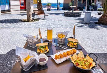Set of nachos and burgers served with fried mozzarella balls and a glass of beer in a restaurant