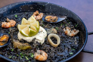 Fototapeta na wymiar Closeup of Arros negre served on a pan in a restaurant