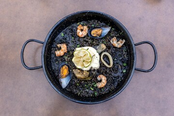 Top view of Arros negre served on a pan in a restaurant