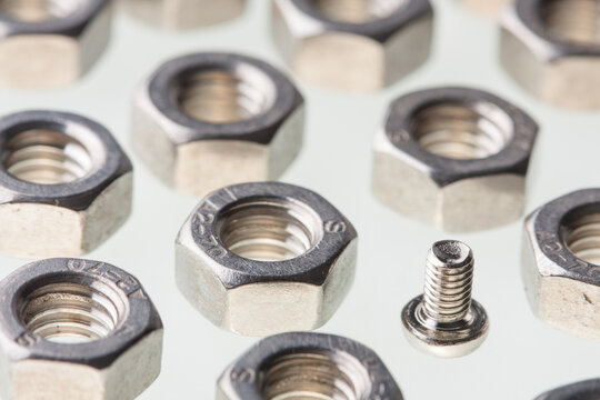 Metallic steel hex nuts and a small fastener bolt