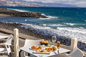 Close-up shot of fried fast food and French toast on a white table with a background of a sea