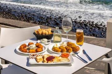 Close-up shot of fried fast food and French toast on a white table with a background of a beach