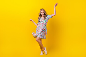 Fototapeta na wymiar Full length photo of adorable positive lady wear flower print dress dancing having fun isolated yellow color background