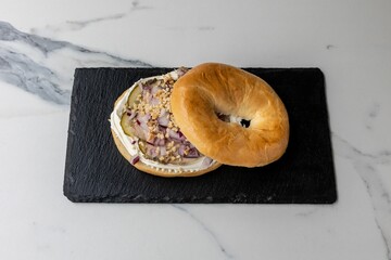 Delicious bagel with onions served on the black board on the marble table