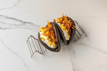 Steamed black gua bao buns with corn served on the marble table