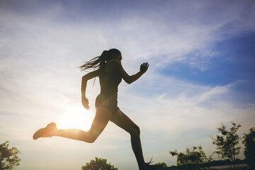 Silhouette of young woman running sprinting on road with motion blur. Fit runner fitness runner...