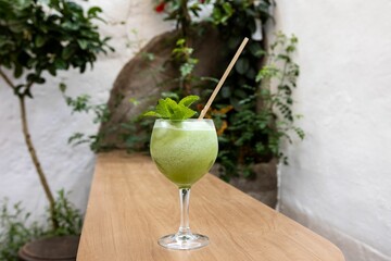 Glass with a delicious fancy iced green mint cocktail in a garden bar