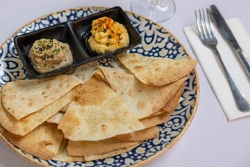 Closeup of toasted tortilla and sauces on a plate laid on a white table